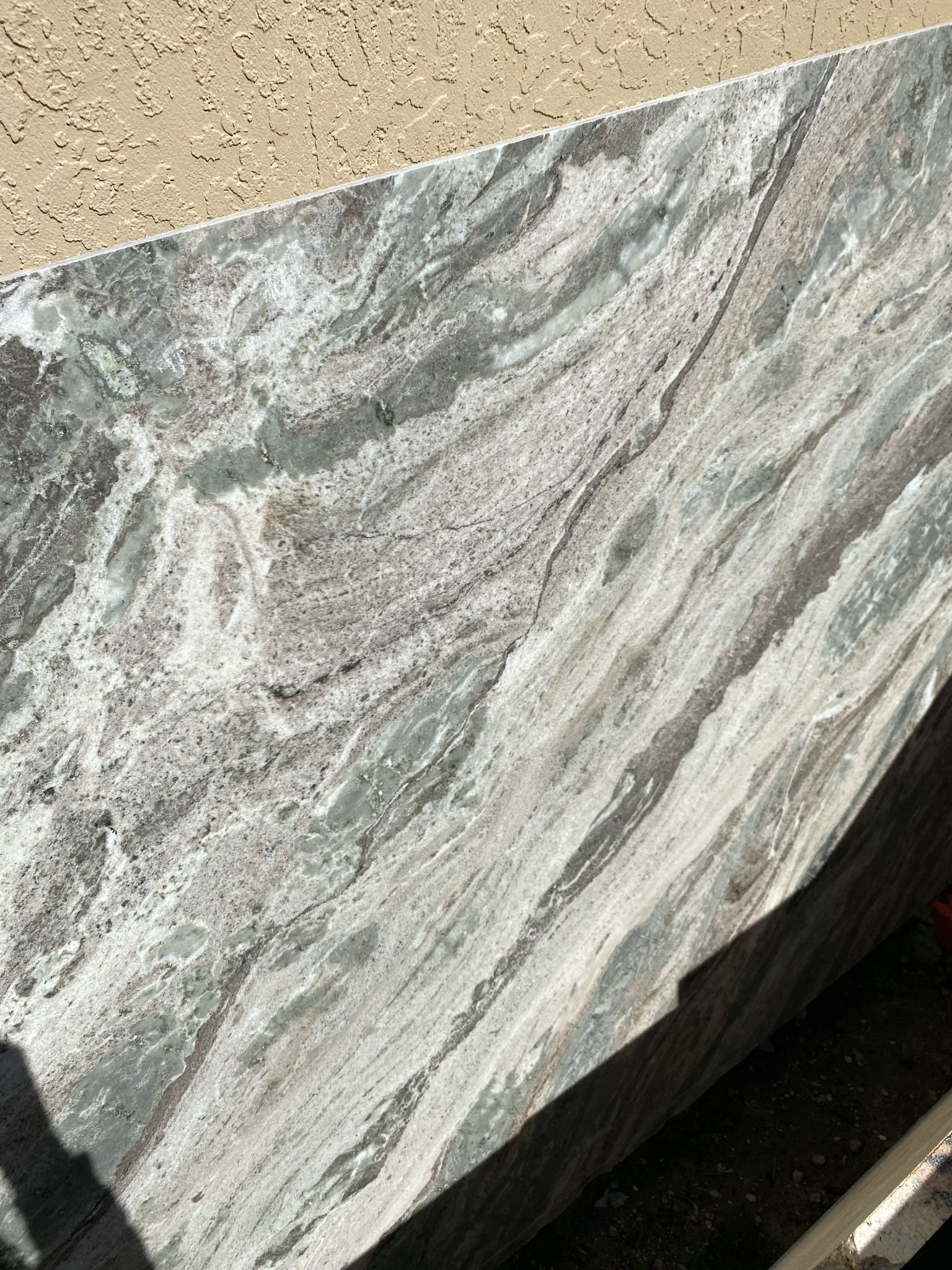 Countertop with flowing patterns in white, gray, and brown. Beige wall in the background.