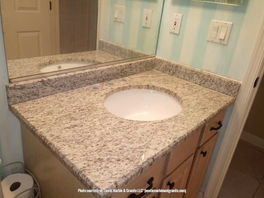 Bathroom vanity with granite countertop, round sink, and light wood cabinets.