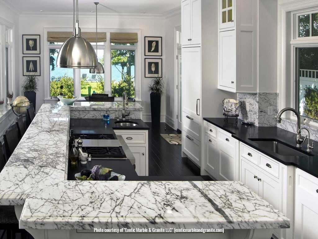 Bright white kitchen with a marble countertop island and black countertops.