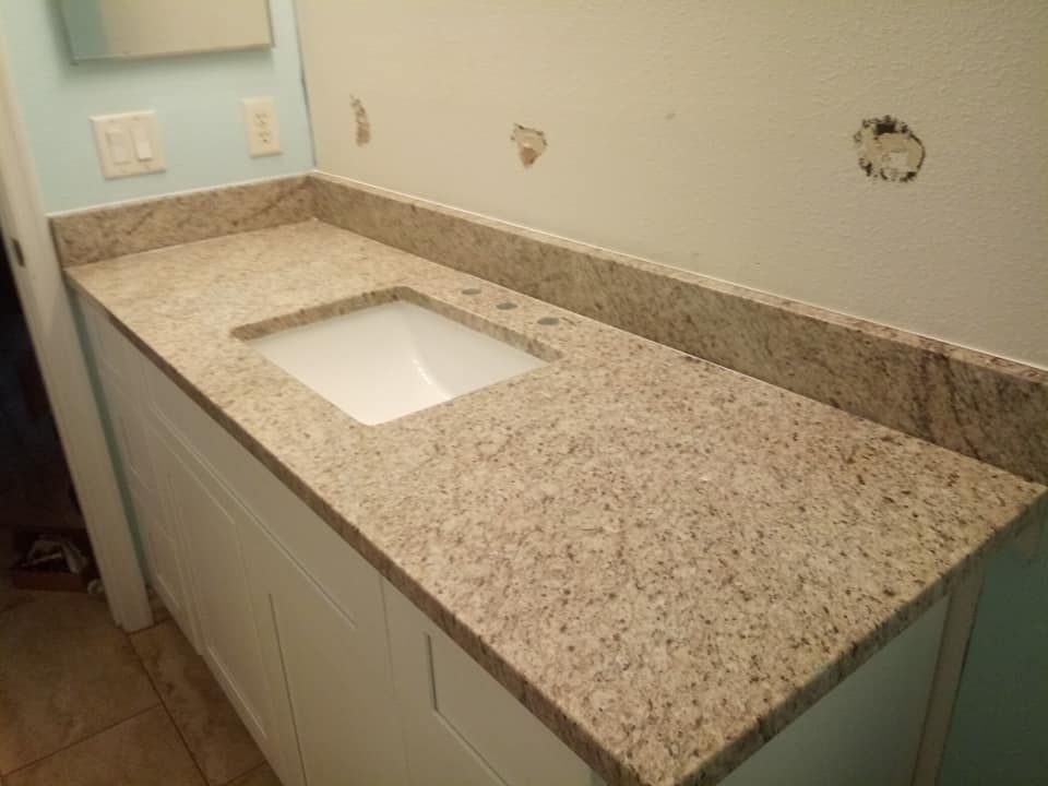 White bathroom vanity with granite countertop and rectangular sink.