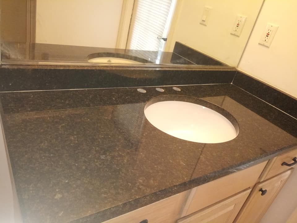 Bathroom vanity with dark granite countertop and a white oval sink.