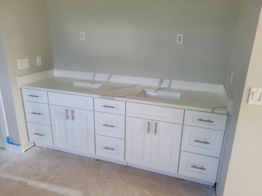 White double vanity with quartz countertop in a bathroom under construction.