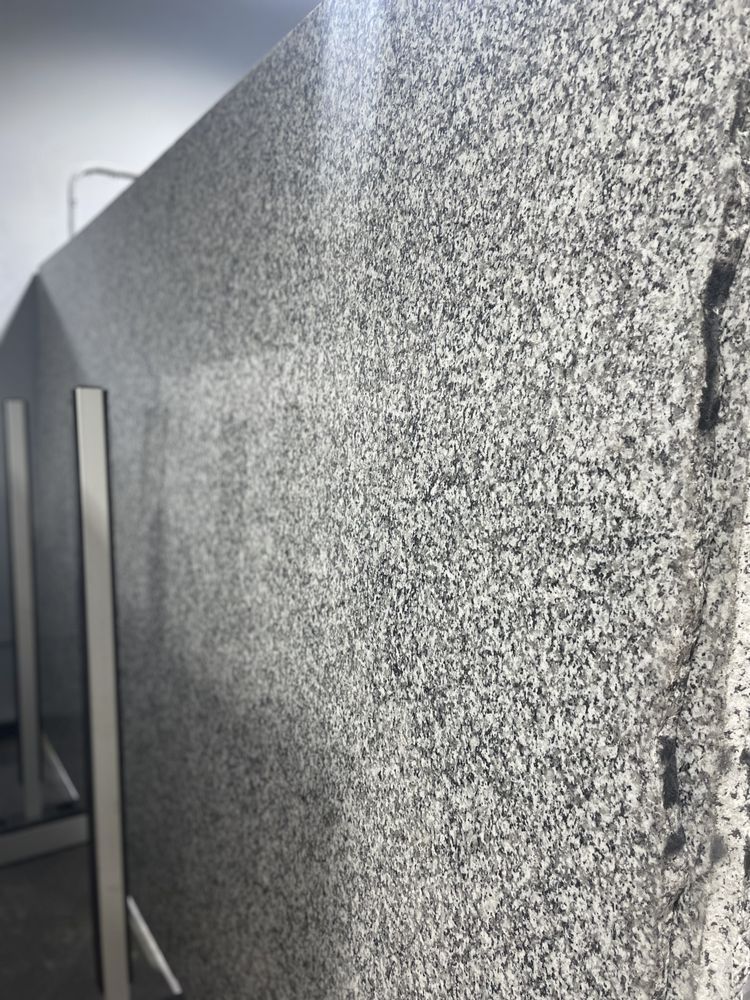 Large slab of gray and white granite, standing upright in a showroom or warehouse.