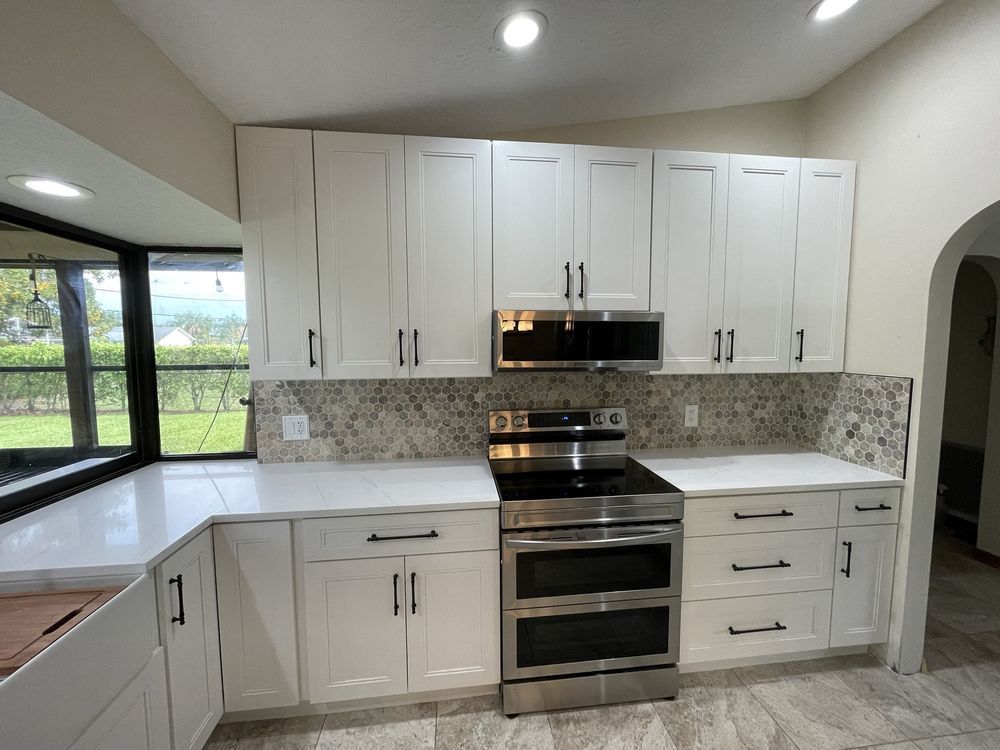 White kitchen cabinets with black hardware and a stainless steel oven.