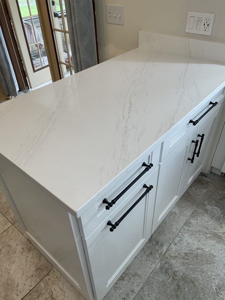 White kitchen island with quartz countertop and black cabinet hardware.