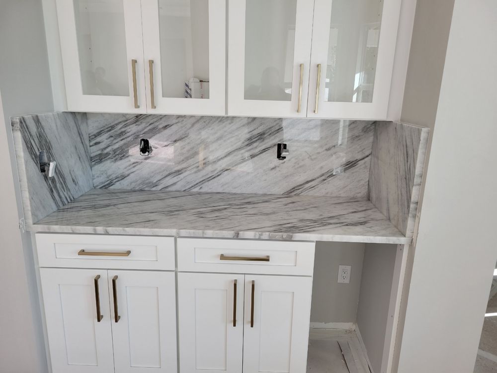 White cabinetry with marble countertop, glass upper cabinets, and gold hardware.