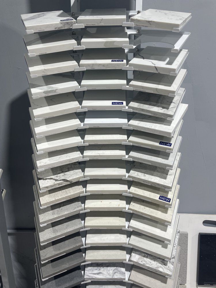 Display rack with numerous rectangular, light-colored stone samples arranged in a curved pattern against a gray wall.