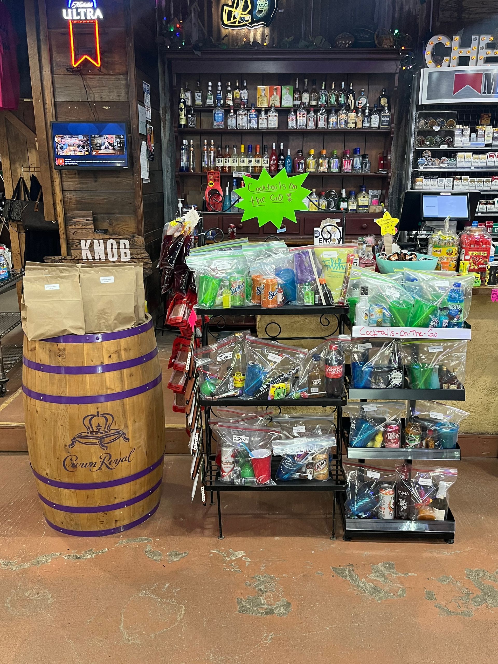 Liquor store interior with shelves of bottles. Displays with gift bags and a barrel.