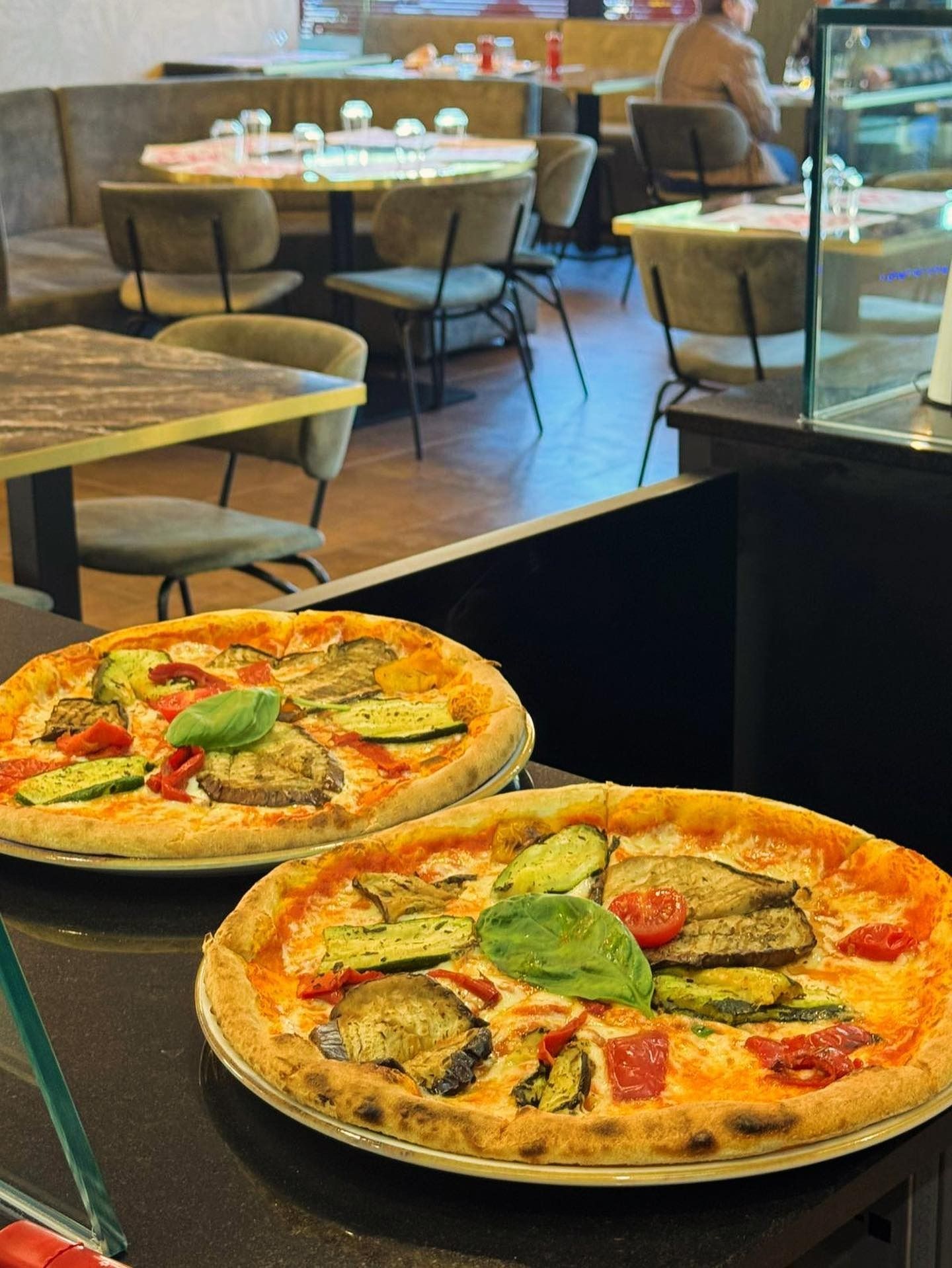 Due pizze su un tavolino da caffè, con i tavoli della sala da pranzo sfocati sullo sfondo.