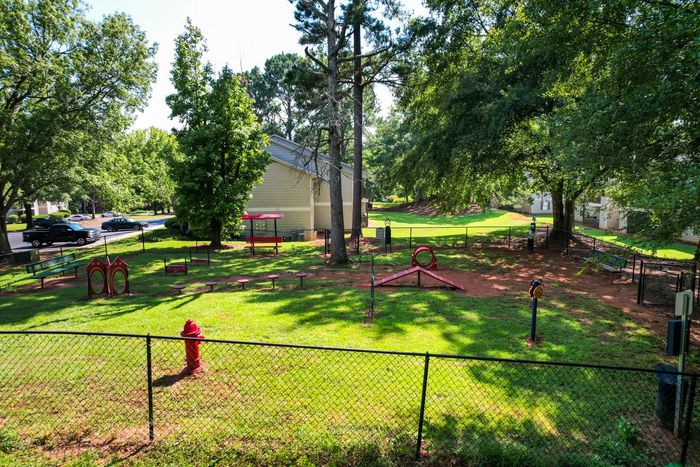 Dog park with agility equipment, fenced with a red fire hydrant.