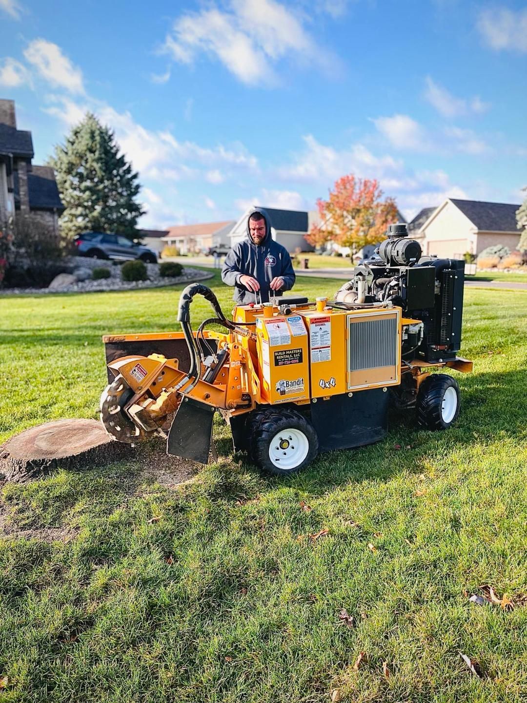 A man is driving a stump grinder in a grassy field.