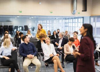 A woman is giving a presentation to a group of people sitting in chairs.