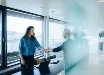 A man and a woman are shaking hands in an office.