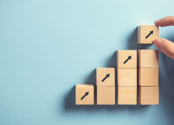 A person is stacking wooden blocks with arrows on them.