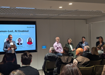 Panel discussion in a conference room with speakers on stage and an audience seated in front