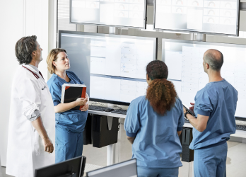 A group of doctors and nurses are looking at a computer screen.