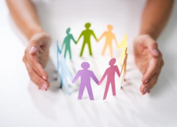 A person is holding a circle of paper people holding hands.