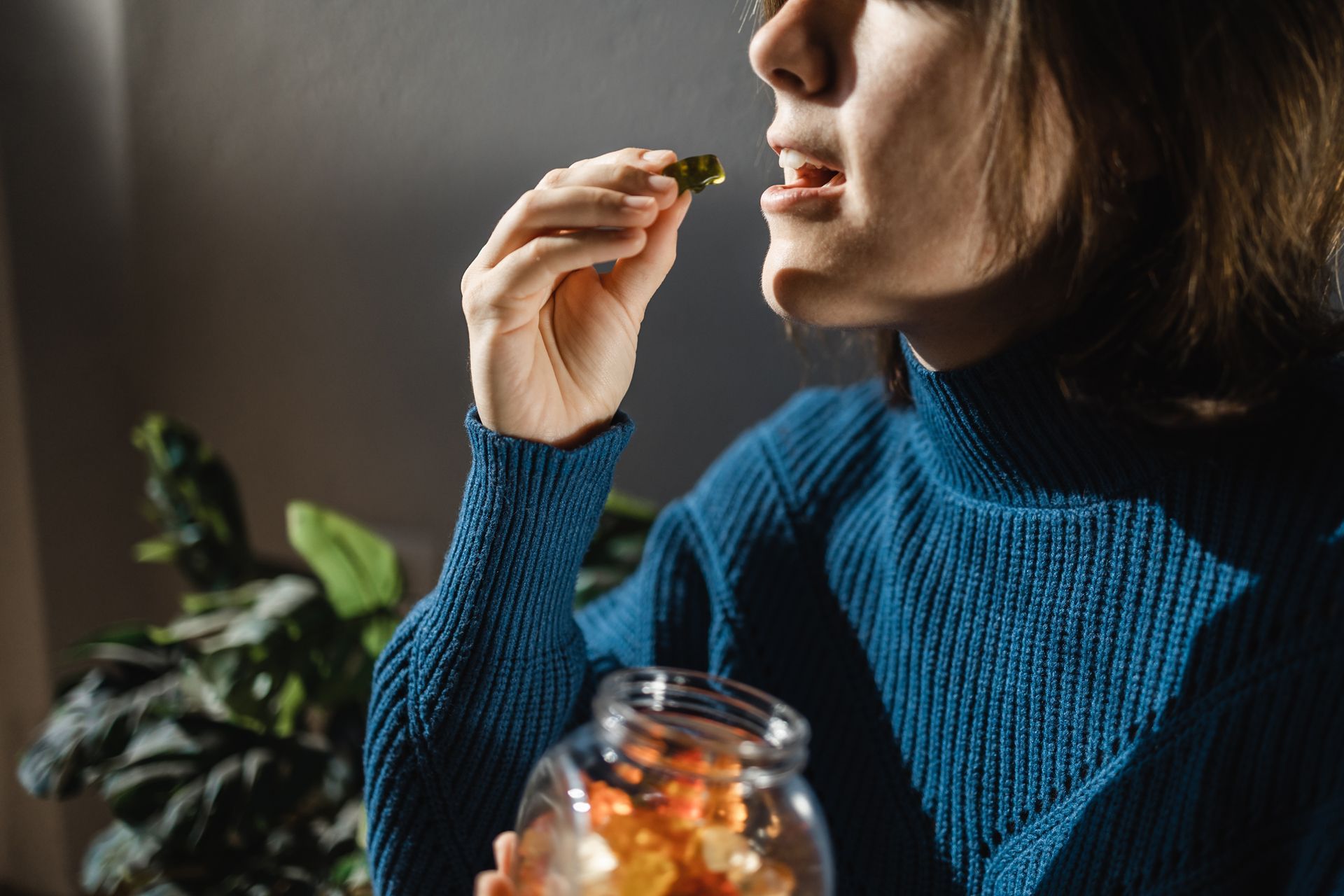 Woman eating from a jar of food, possibly pickles, in a well-lit room
