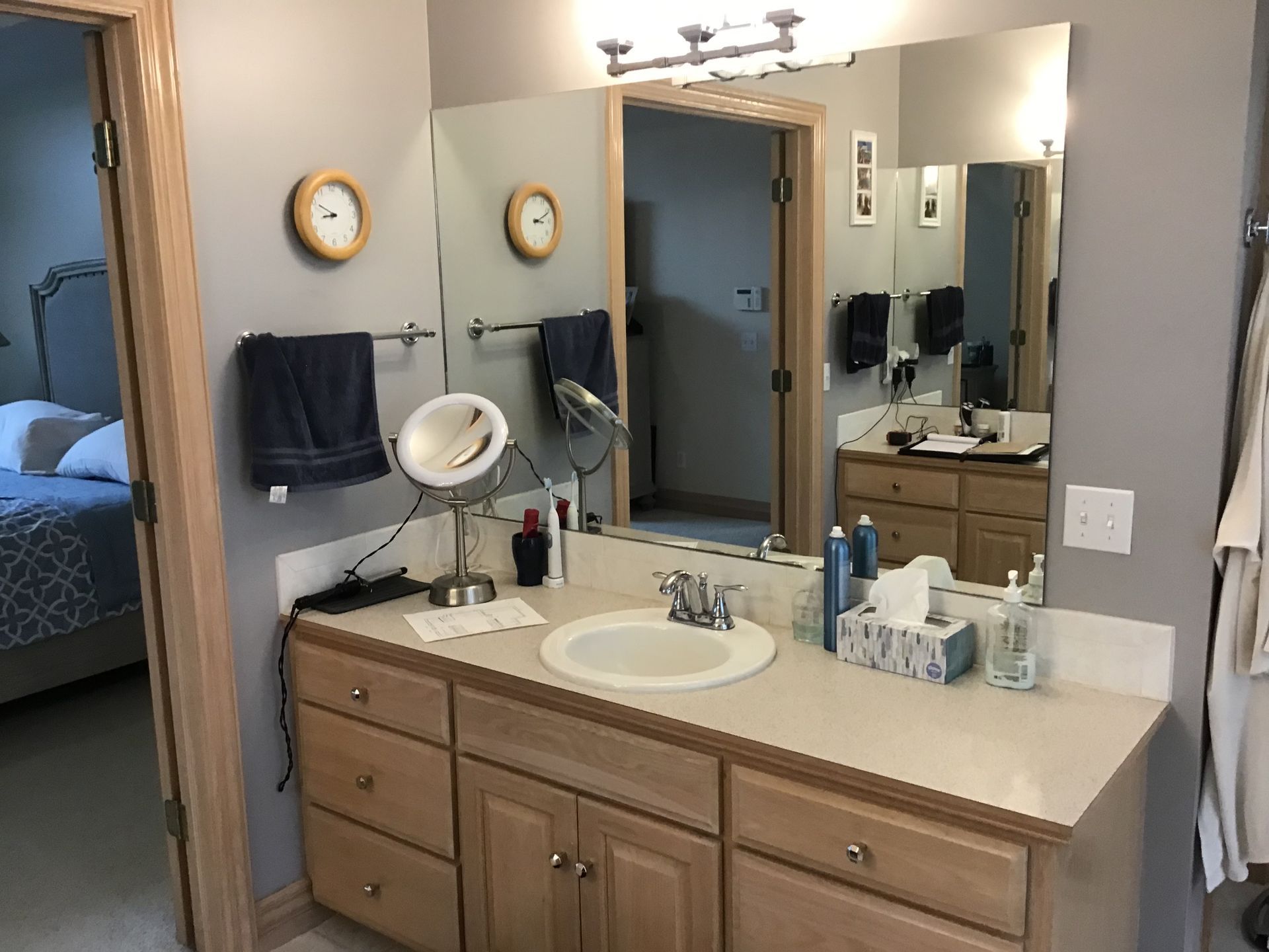 Bathroom vanity with sink, mirror, toiletries, and towel rack in a beige home interior
