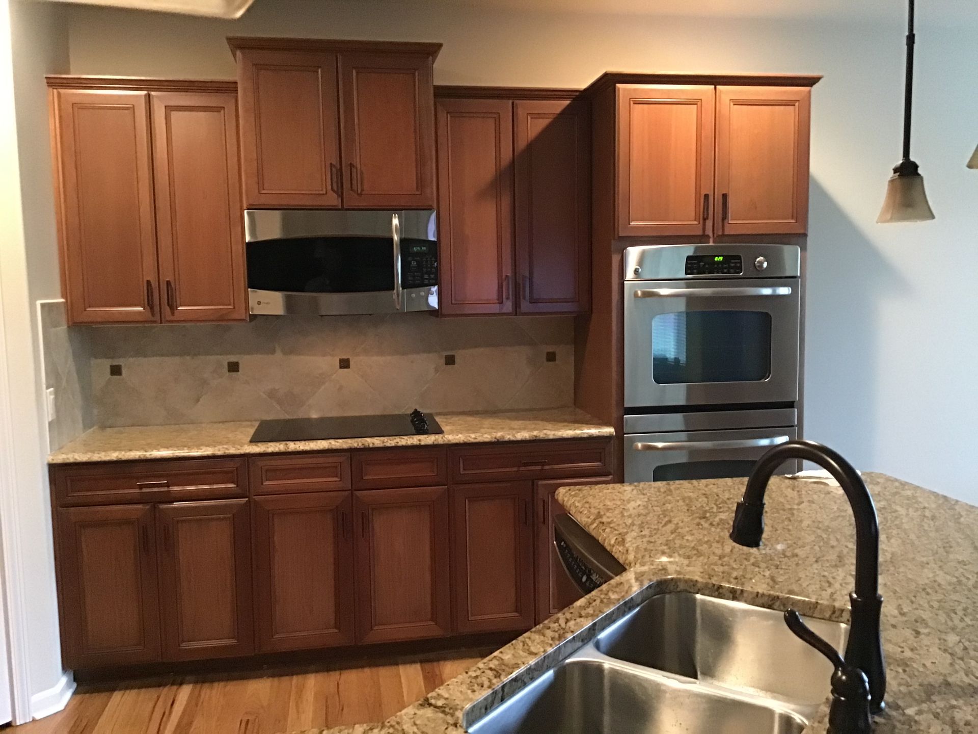 Kitchen with wooden cabinets, granite counters, stainless appliances, and a dark faucet over the sink.