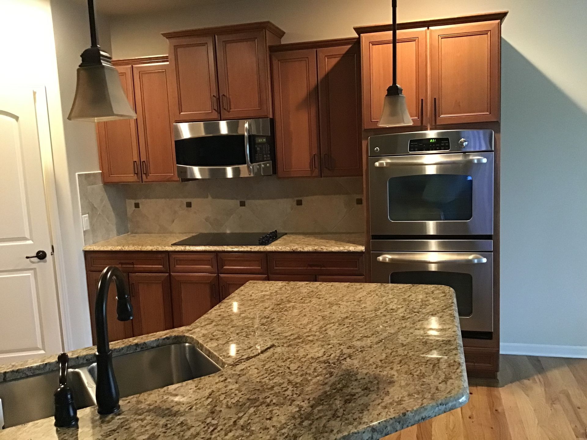 Modern kitchen with wood cabinets, granite island, stainless steel appliances, and pendant lights