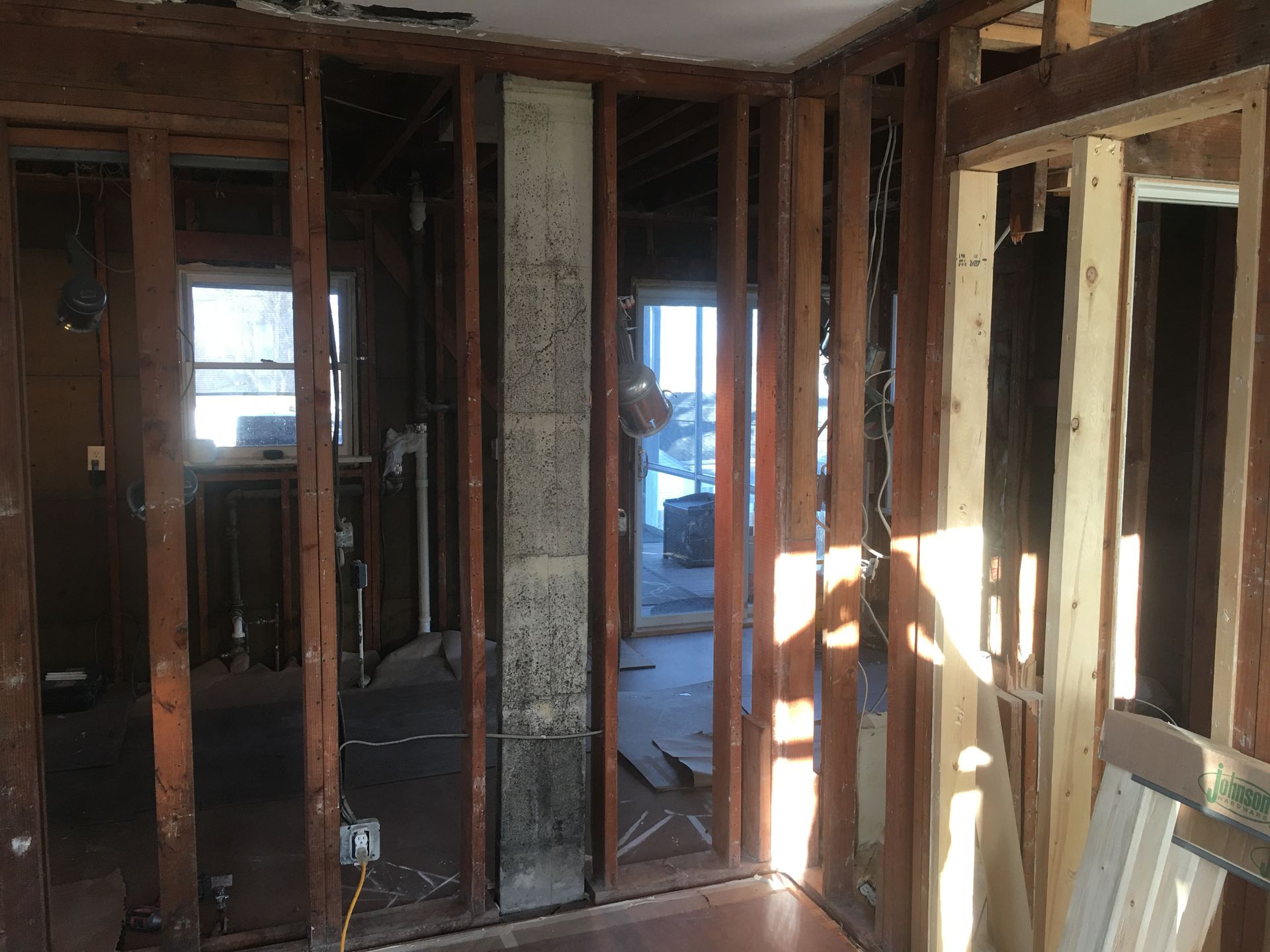 Partially demolished room with exposed studs, broken walls, and sunlight streaming through openings