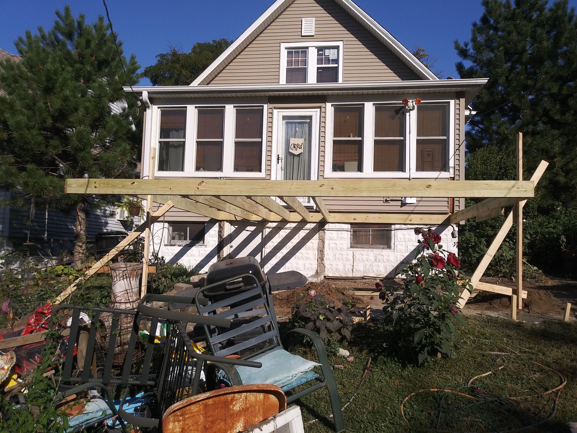 House under repair with wooden scaffolding and construction debris in the yard.