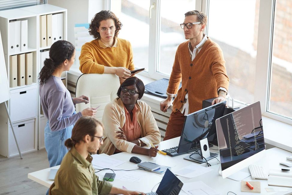 A group of people are standing around a table in an office.