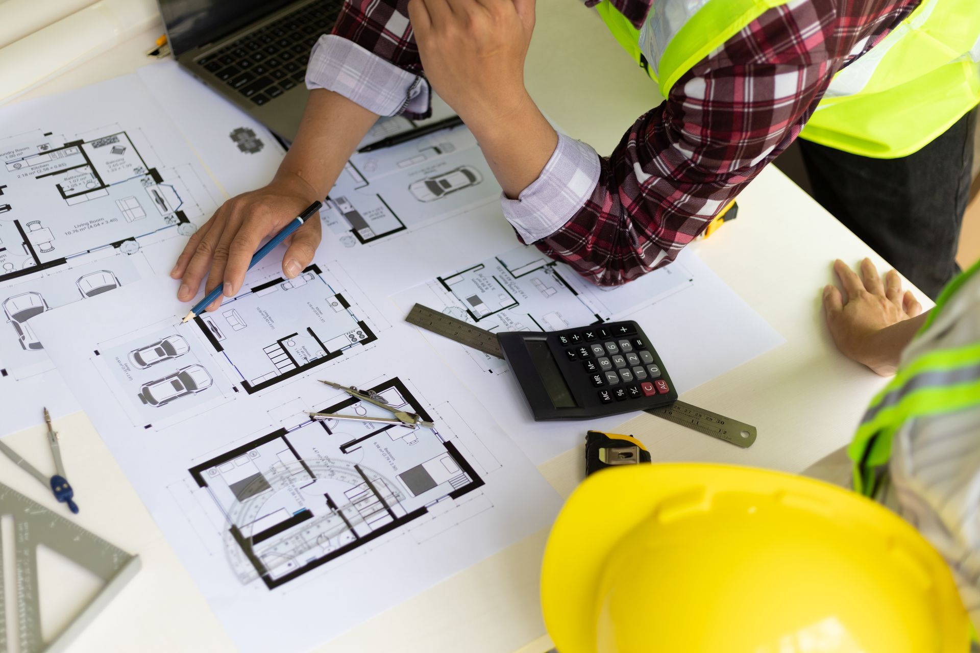 A man is sitting at a table looking at a blueprint of a house.
