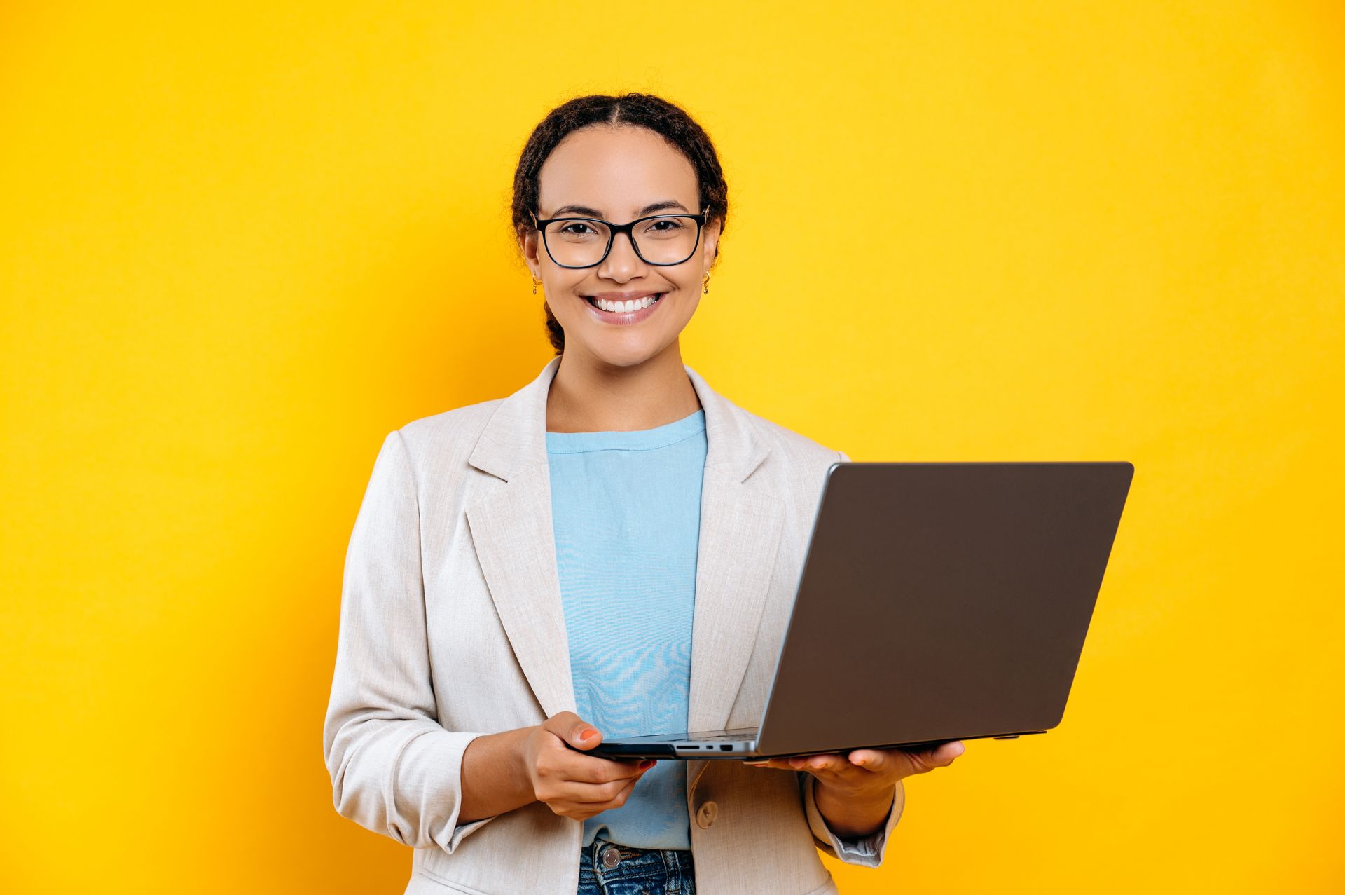 A woman is holding a laptop computer in her hands and smiling.