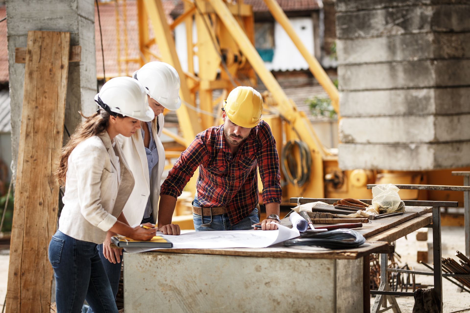 A group of construction workers are looking at a blueprint at a construction site.