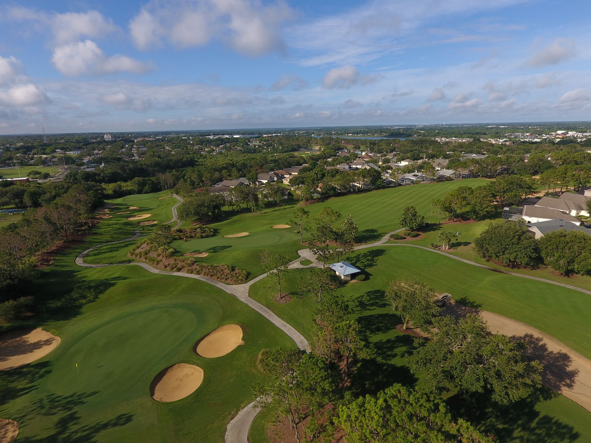 An aerial view of a golf course with houses in the background.
