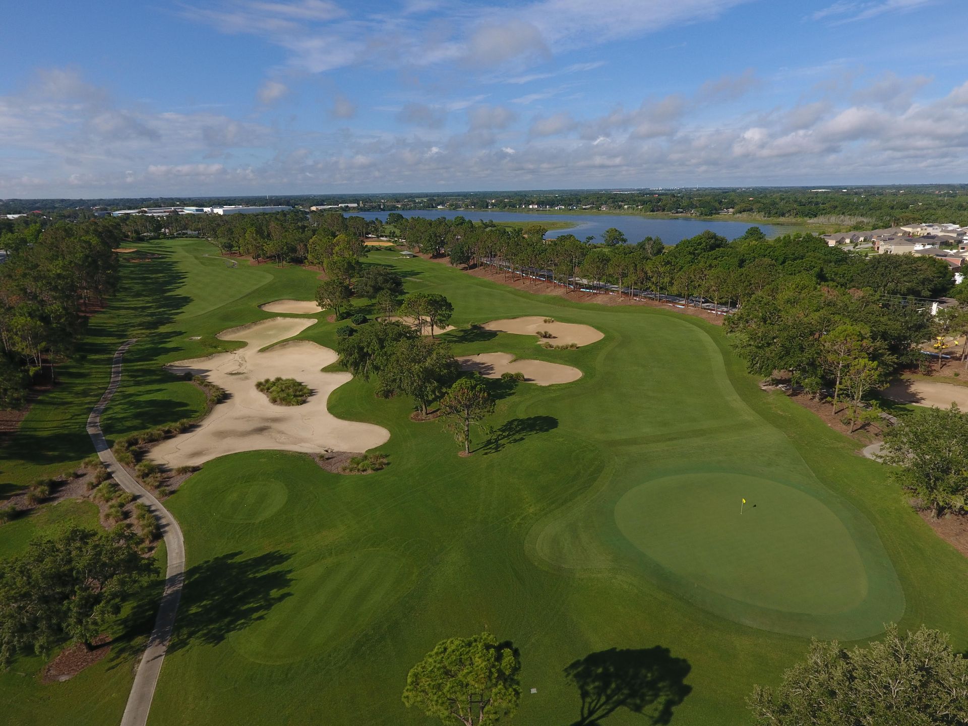 An aerial view of a golf course with a lake in the background.
