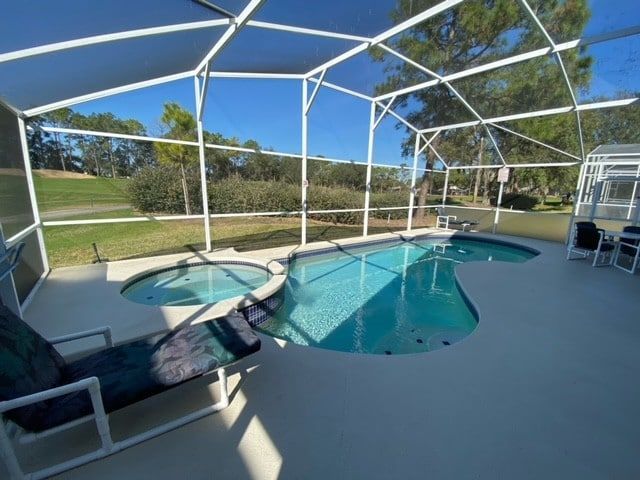 A patio with a table and chairs next to a pool.