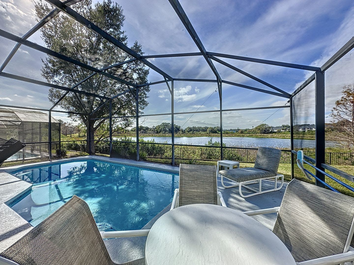 There is a swimming pool in the backyard with a screened in area.
