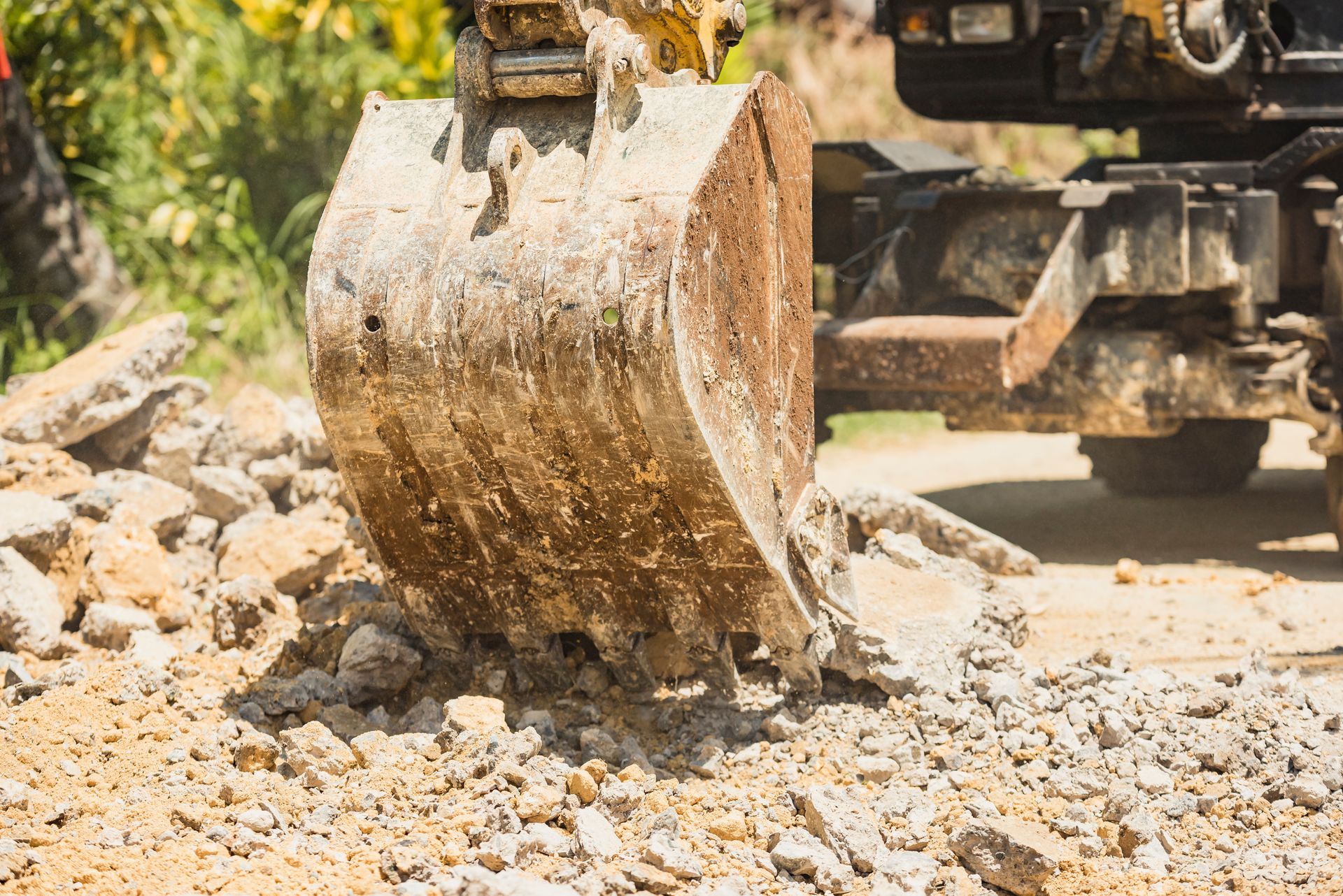 Un bulldozer déplace des rochers sur un chemin de terre.