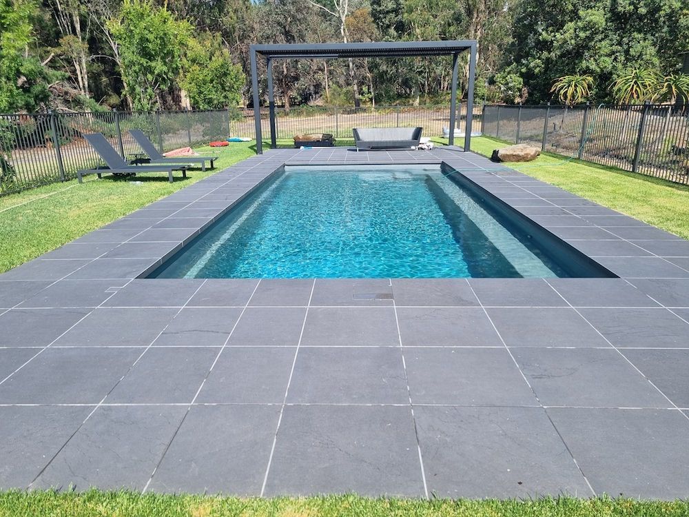 Swimming pool with blue tiles, white coping, and steps.