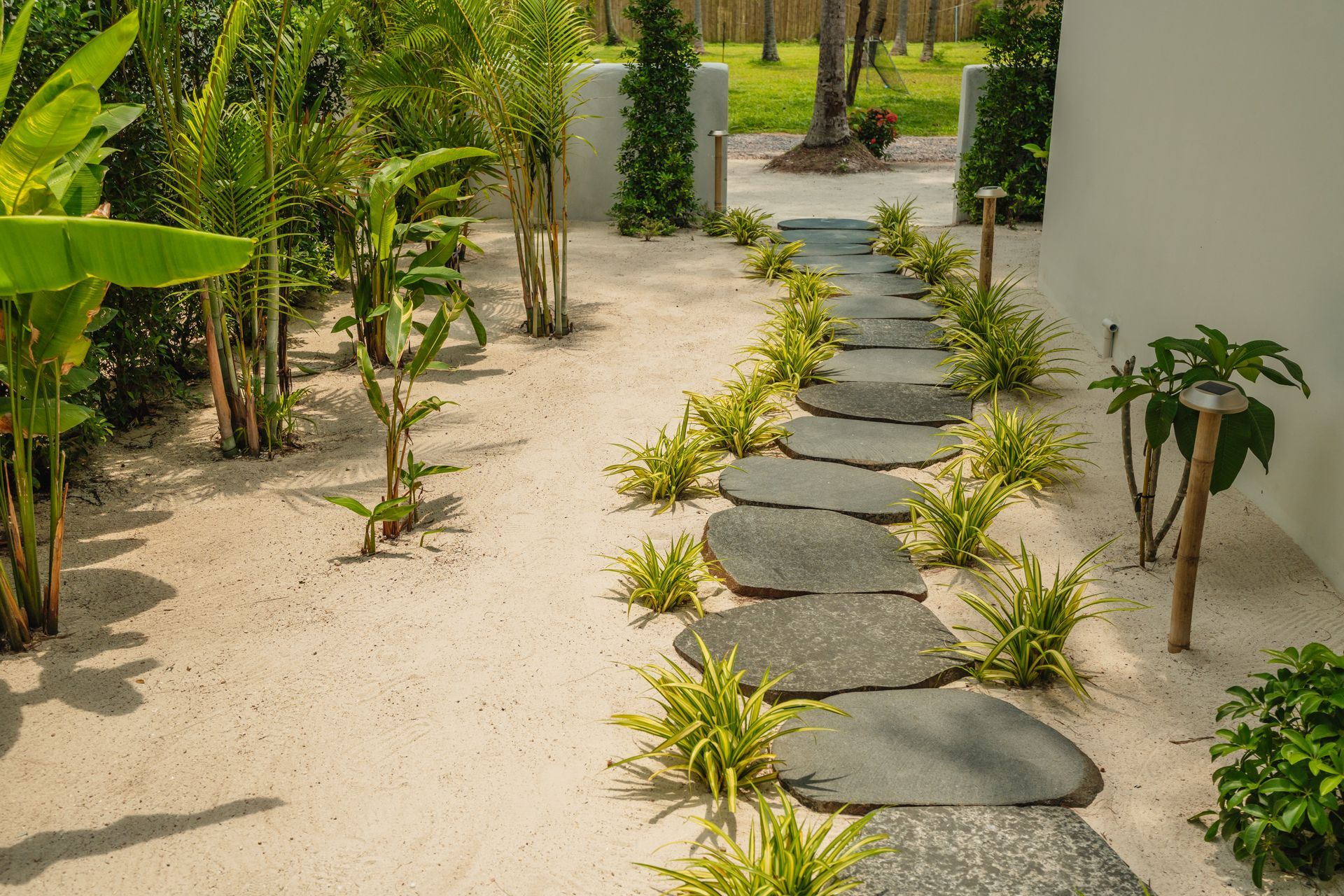 Stone-walled pond with a dark fountain in the center; gravel path and green field in background.