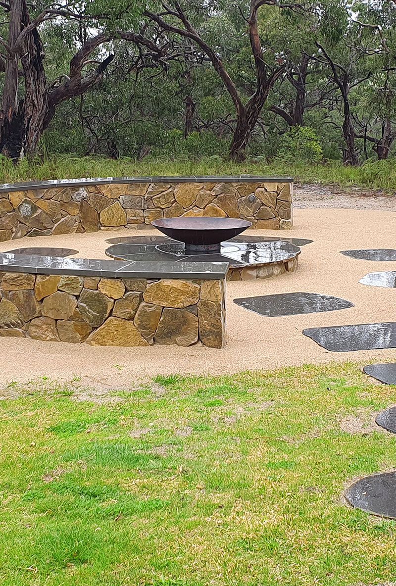 Man installing sod in a backyard, sunny day. Rolls of sod on the ground near a wooden deck.