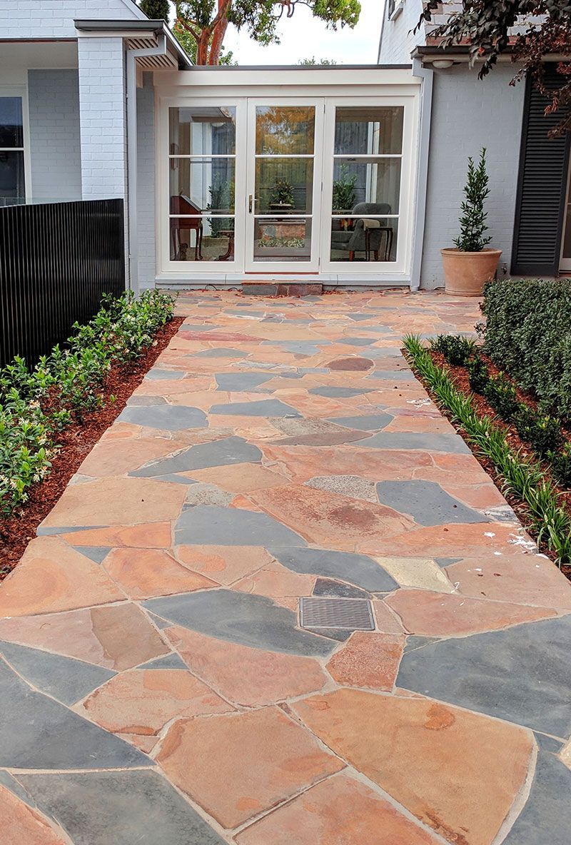 Stone path winds through lush, green hillside garden.