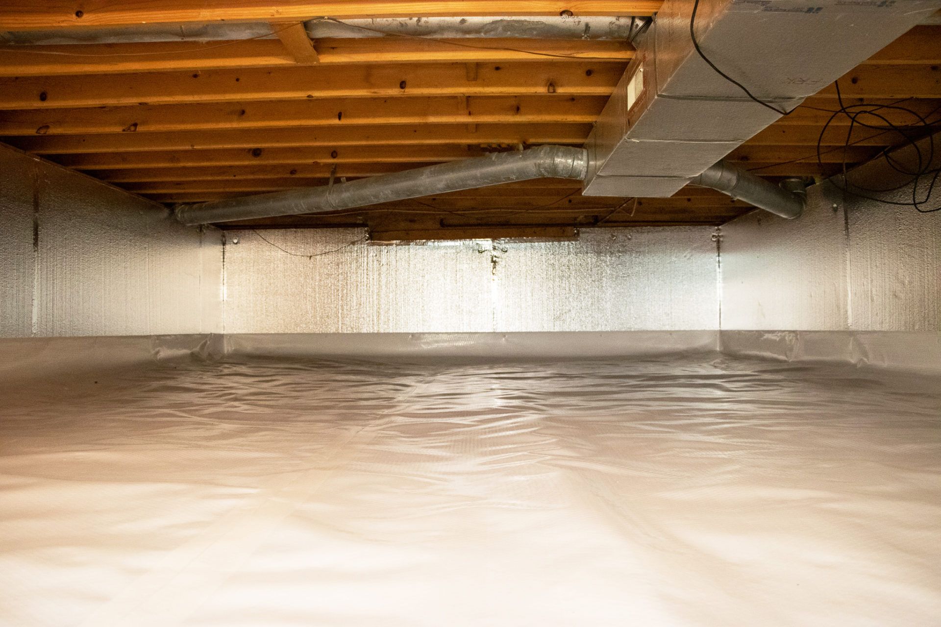 Modern single-story home exterior with gray horizontal siding, a dark metal roof, and a central wood-paneled front door.