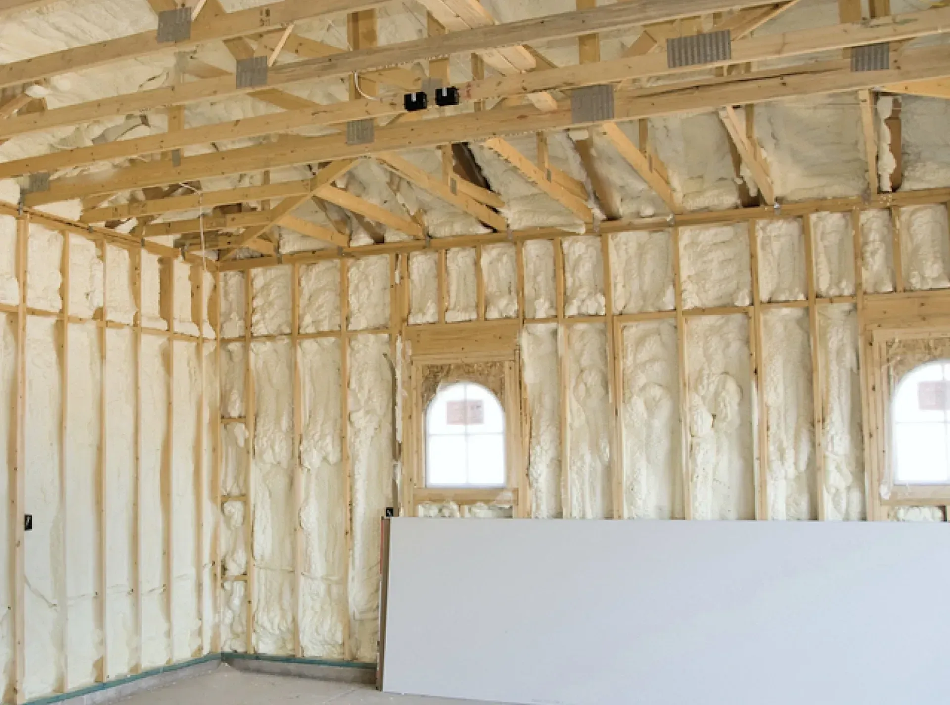 Modern single-story home exterior with gray horizontal siding, a dark metal roof, and a central wood-paneled front door.