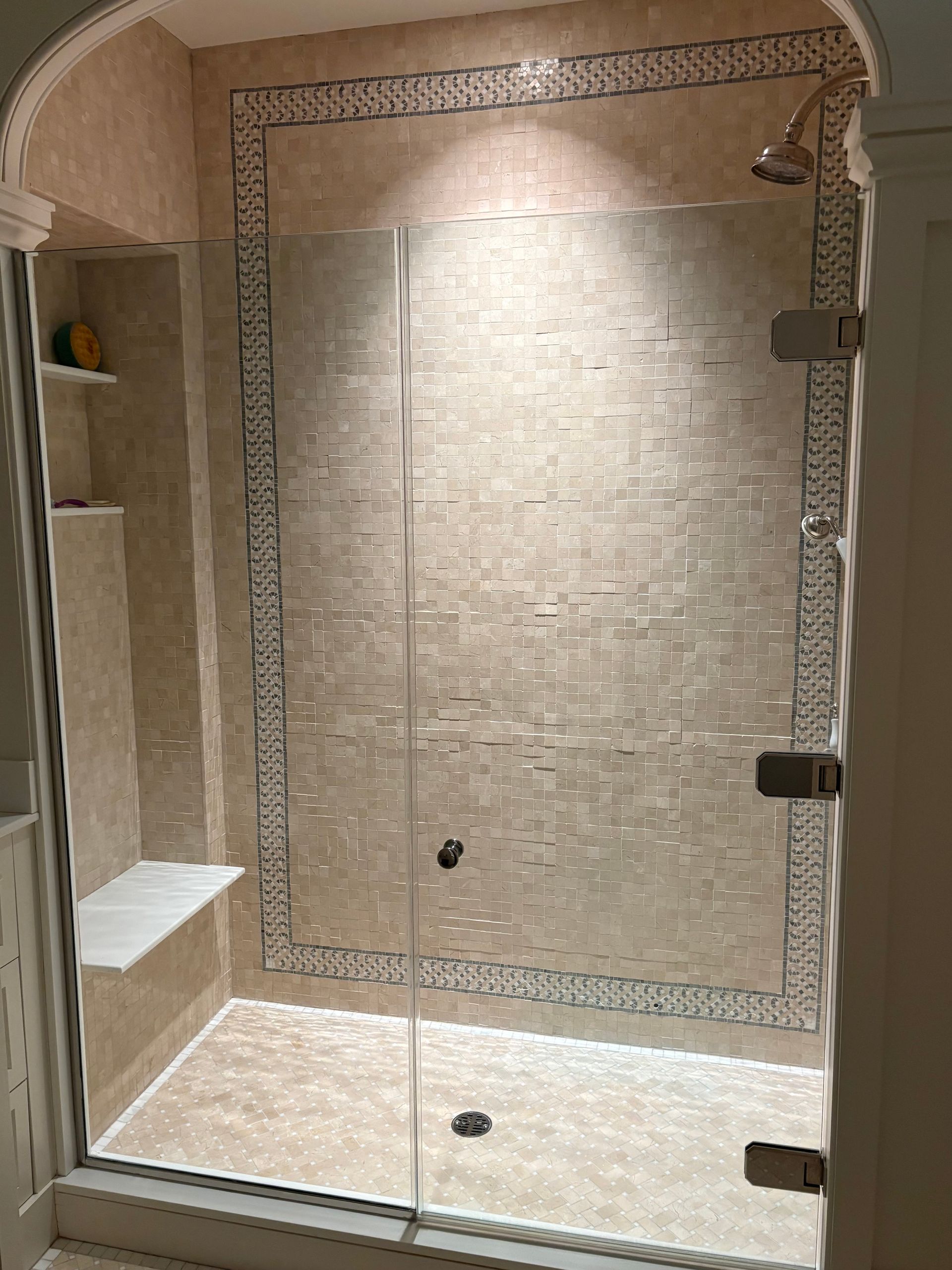 Shower stall with beige tile and clear glass door