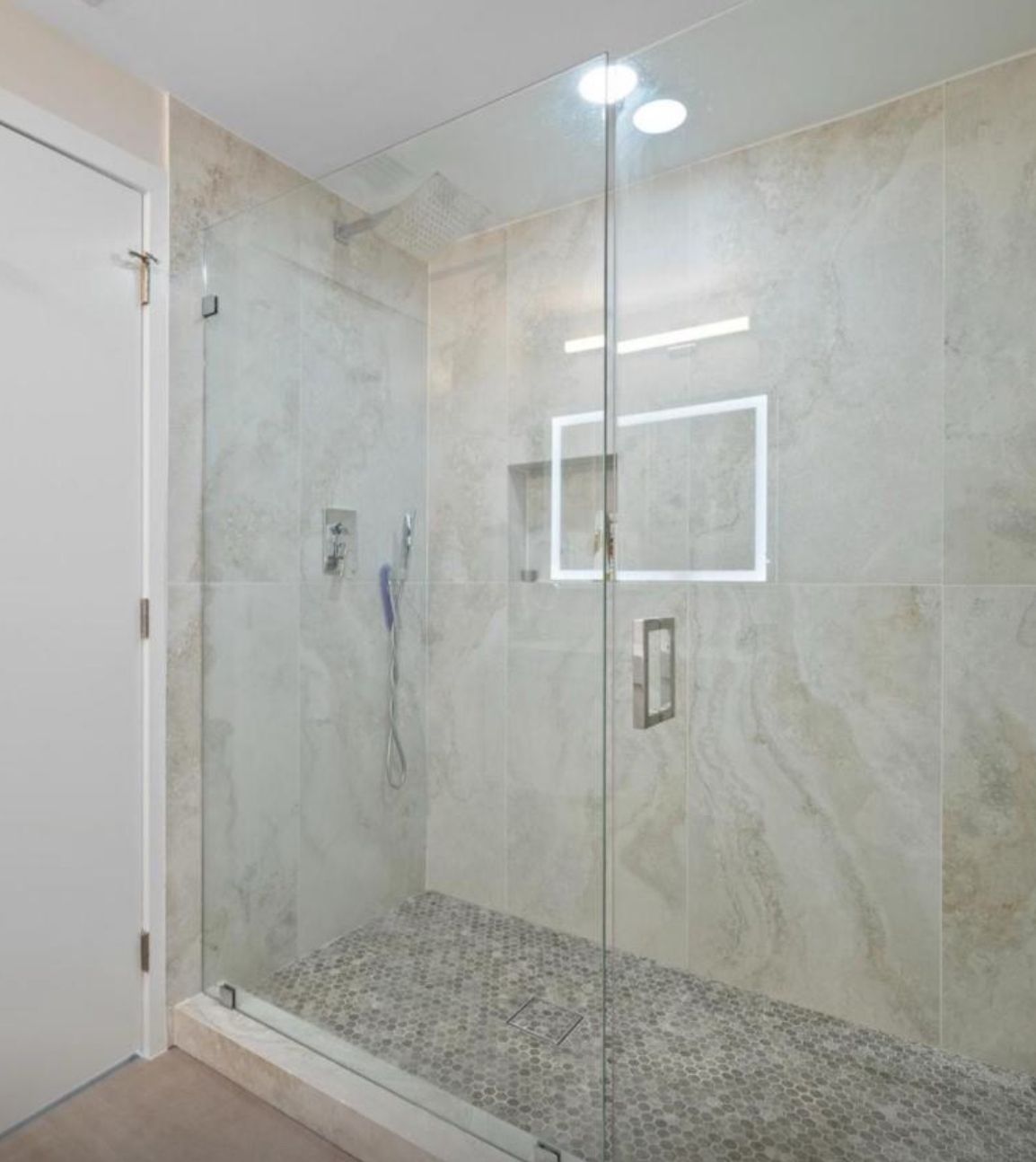 A modern walk-in shower with pebble floor