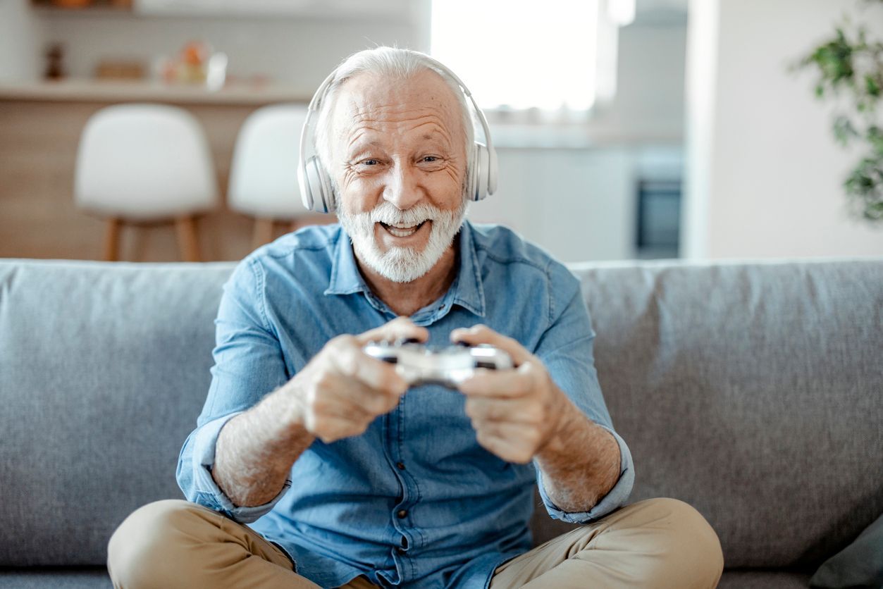 Senior man with headphones on playing video games at home