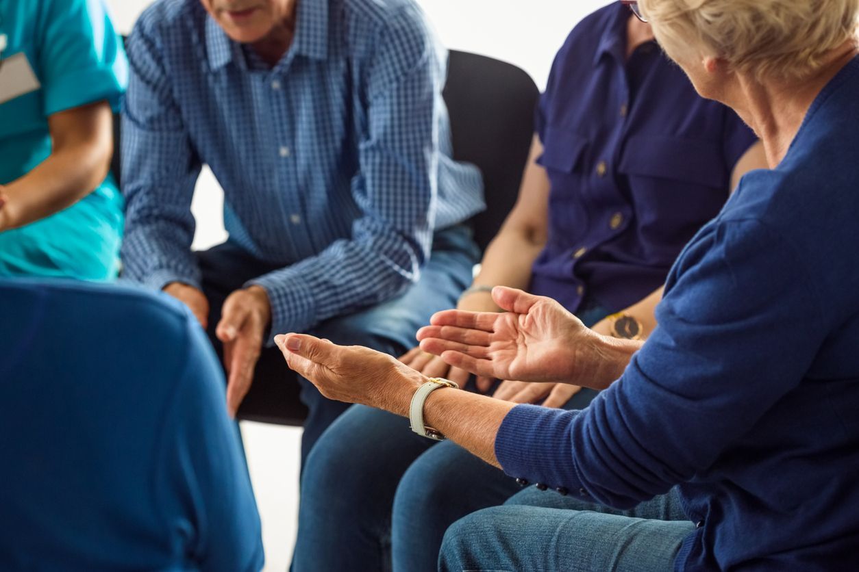 Alzheimer’s support groups concept - Woman sharing issues with caregivers during a group meeting.
