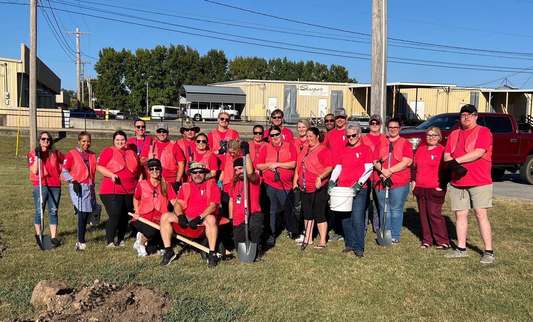 A group of people in red shirts are standing in a field.