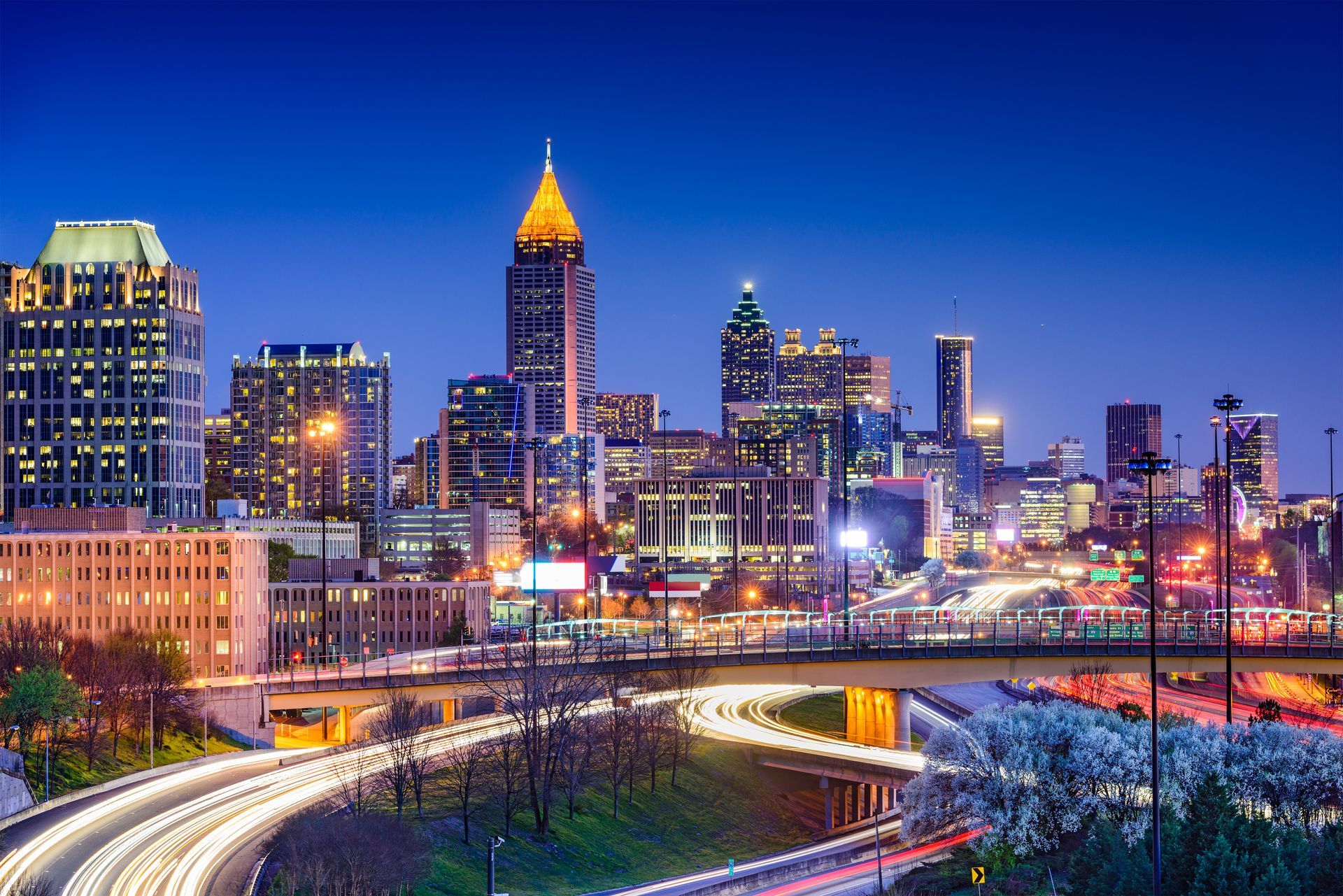 A city skyline at night with a highway in the foreground.