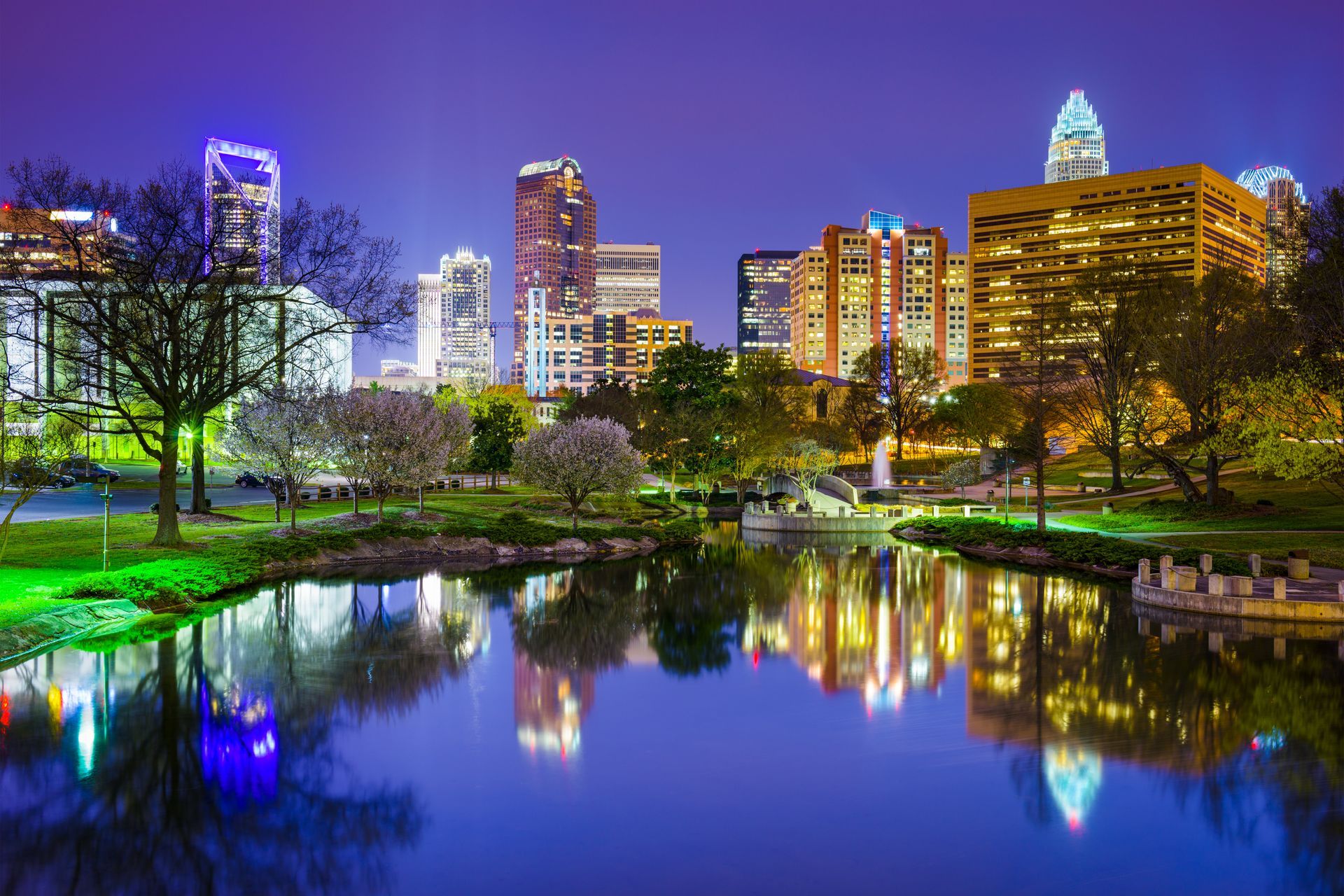 A city skyline is reflected in a lake at night.