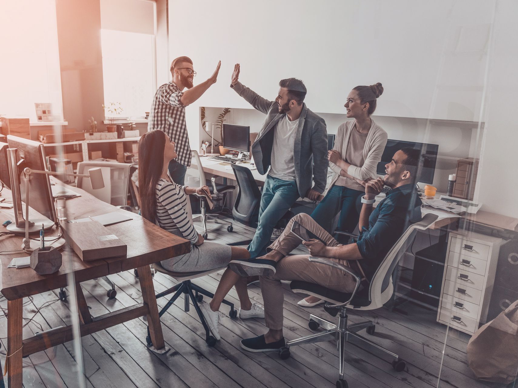 A group of people are giving each other a high five in an office.